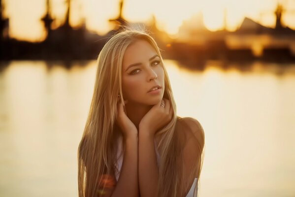 Bella ragazza sullo sfondo di acqua e tramonto