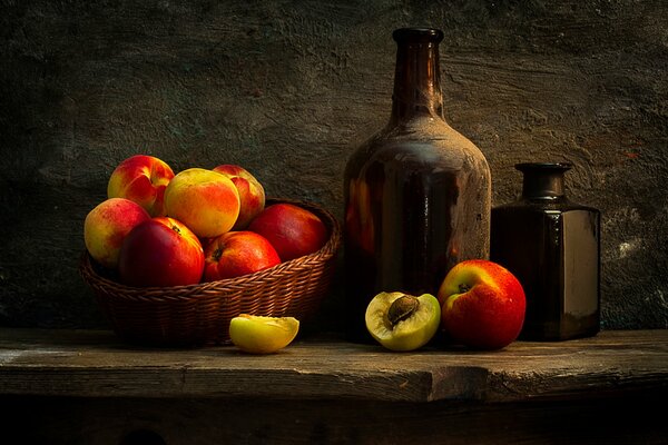 A basket of peaches and bottles on the table