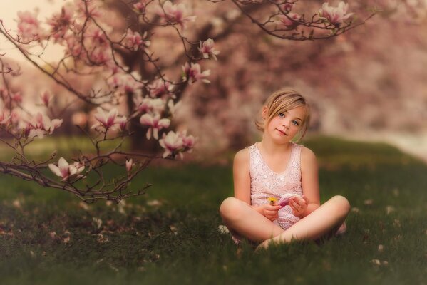 A girl with an apple in spring under the flowers of a tree