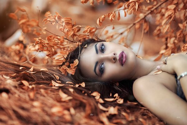 A girl with beautiful makeup and leaves around