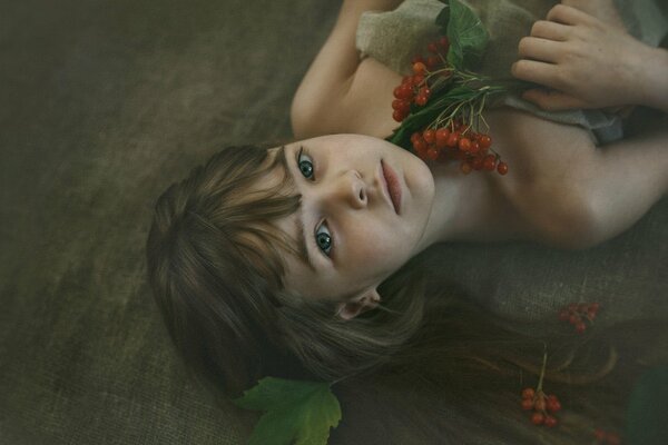 The girl is lying with a branch of viburnum