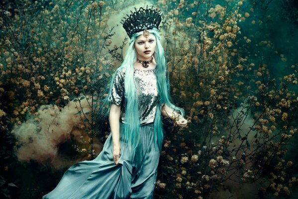 Bella Kotak with turquoise hair on the background of a blooming garden