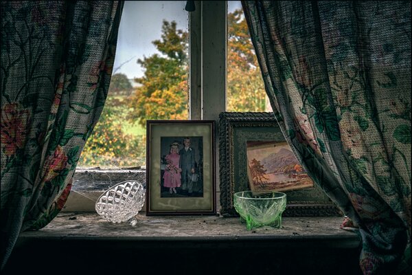 Une photo d un rebord de fenêtre avec de vieilles photos et des vases sur un fond de feuillage d automne