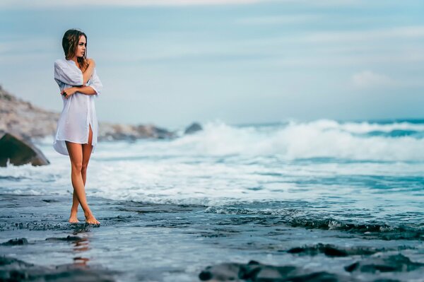 Chica en camisa en la orilla del mar