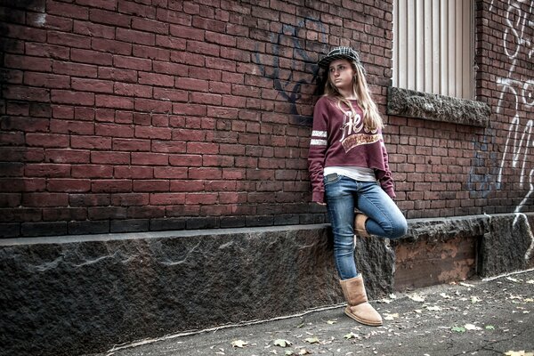 A girl in an urban style at a brick wall