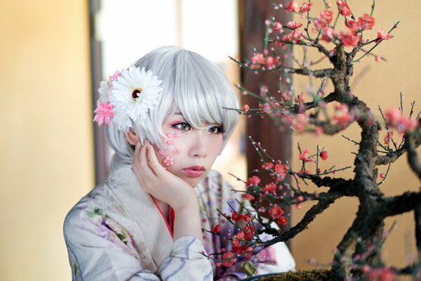 Asian girl looks at blooming bonsai