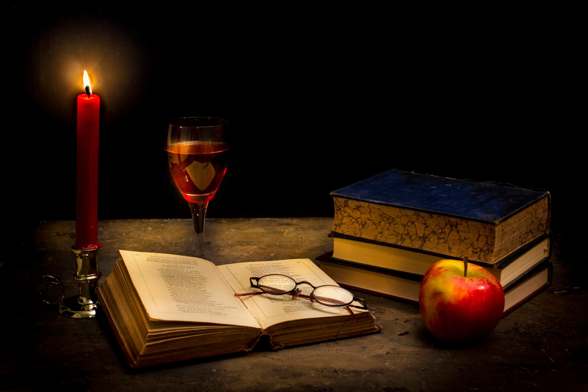 calme dans l obscurité bougie livre lunettes verre à vin pomme