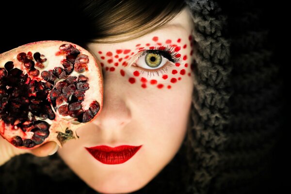 Makeup of a girl with a pomegranate in her hand