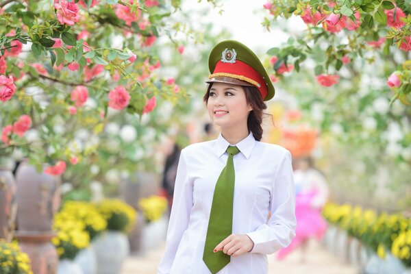 A girl in a green cap walks in a park among flowering trees