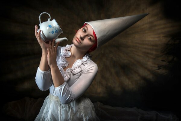 Девушка в странной шляпе держит чайник