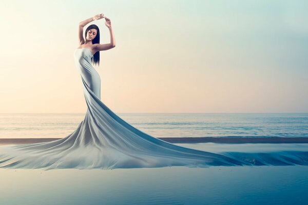 Mädchen im fließenden Kleid auf dem Hintergrund des Meeres