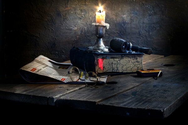 On the table are glasses, a book, a candle, a pipe