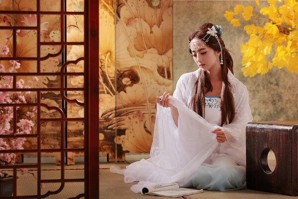 Asian woman in a white dress sitting on the floor in the house