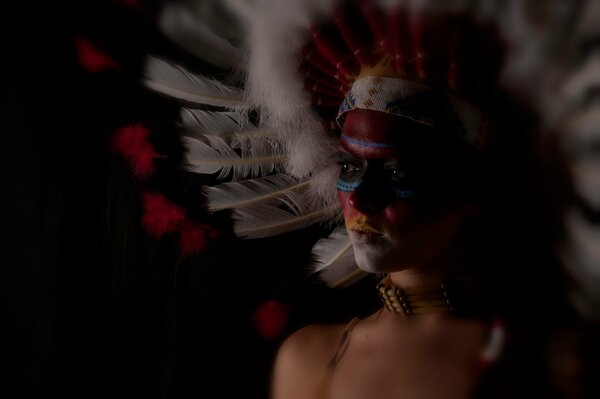 A girl in a semi-profile, painted in the style of Indians with a feather headdress on her head