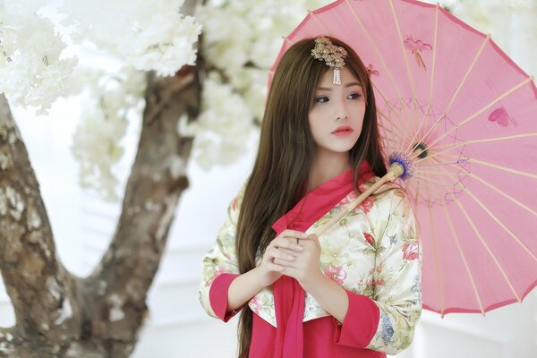 Asiatische Frau posiert im Garten mit einem Regenschirm