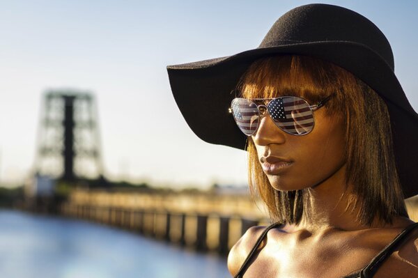 A girl in a hat and glasses reflecting the flag of America