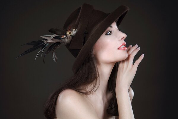 Foto de una chica con un sombrero con una pluma