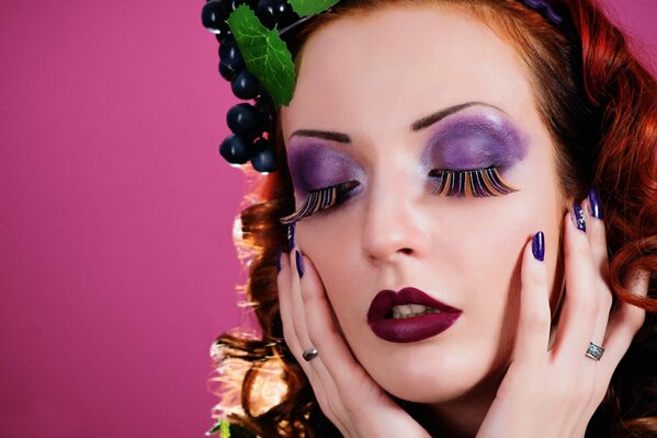 Portrait of a girl with interesting makeup and grapes in her hair