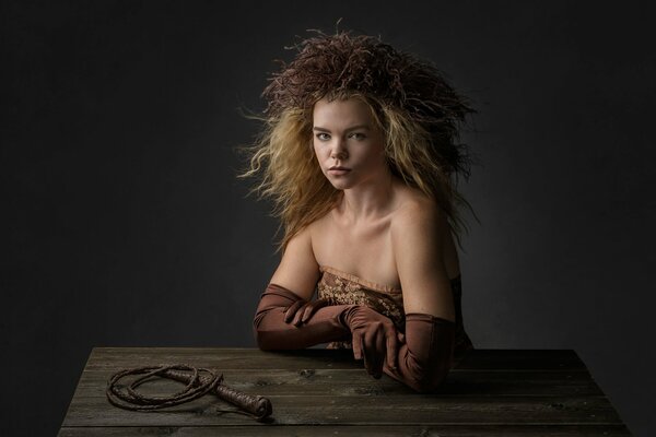 Portrait d une jeune fille à la table avec des gants et un fouet