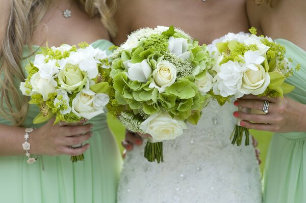 Mariée avec des copines tenant des bouquets blancs et verts