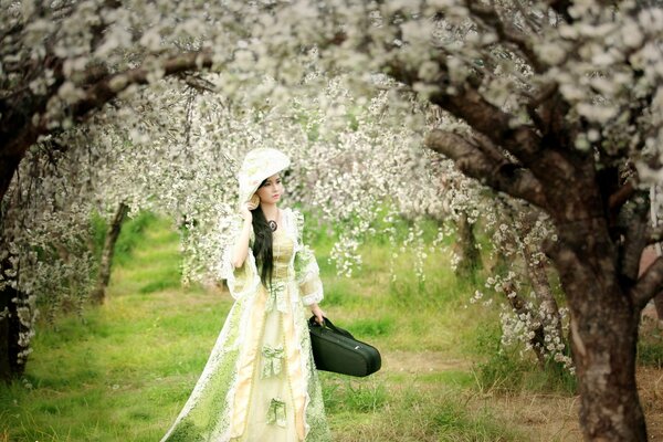 A girl in a green dress in a blooming garden