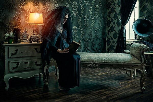 A woman in a black veil and a black dress reads a book in a dark room