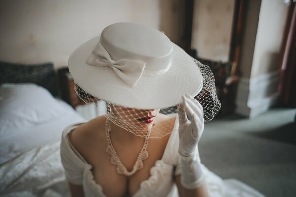 Image of the bride: white dress, hat, gloves, necklace