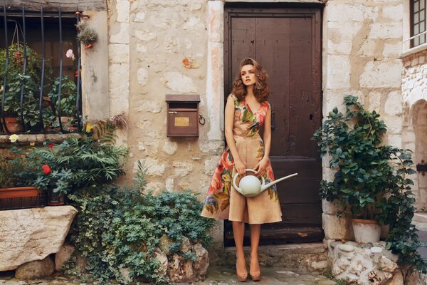 A girl in an antique dress with a watering can in her hands