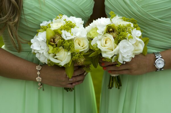 Two girls in identical greenish dresses and with bouquets