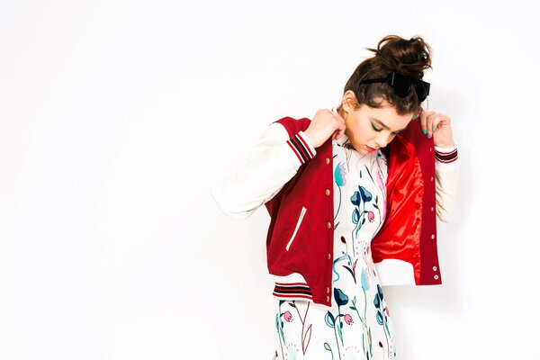 A girl in a white dress with flowers and a red bomber jacket