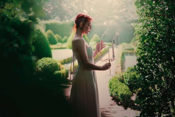 Ragazza in giardino in abito con candele