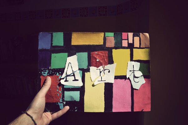 The hand holds a picture that shows a lot of colorful squares