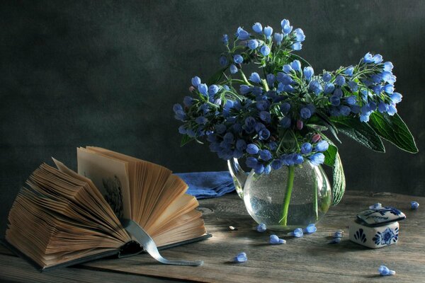 Libro abierto en una mesa junto a un jarrón de flores