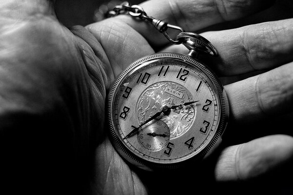 Fotografía en blanco y negro de un reloj de pulsera en la palma de su mano