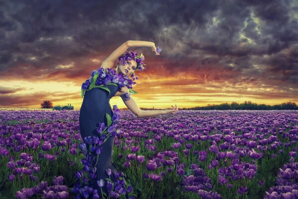 Mädchen steht in einem Feld mit Blumen bei Sonnenuntergang