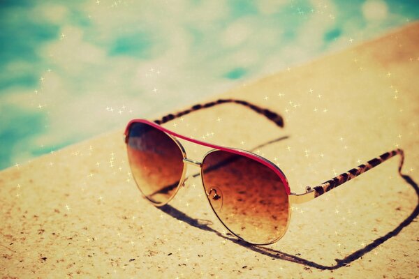 Stylish glasses lie on a sandy background