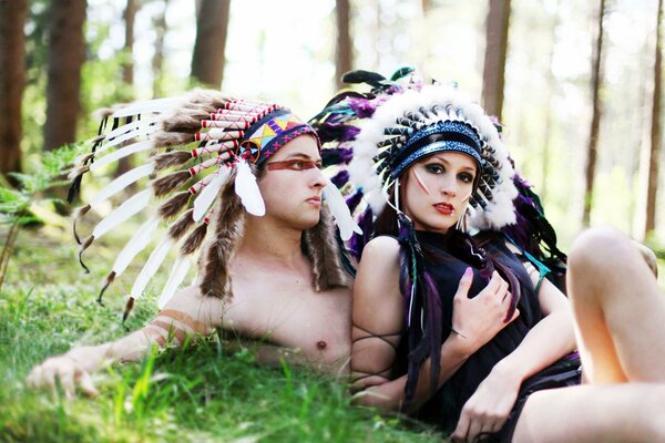 Chica y chico en plumas en el bosque descansando