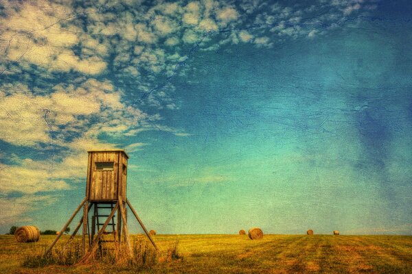 Among the harvested hay on the field there is a wooden guardhouse