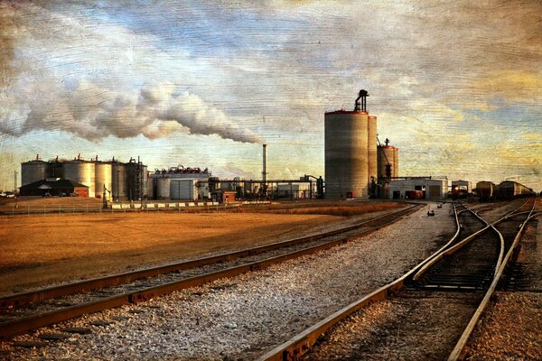 Imagen del ferrocarril, la fábrica, el humo y el cielo