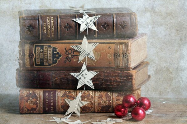 A stack of old battered books with a garland of paper stars and red balloons