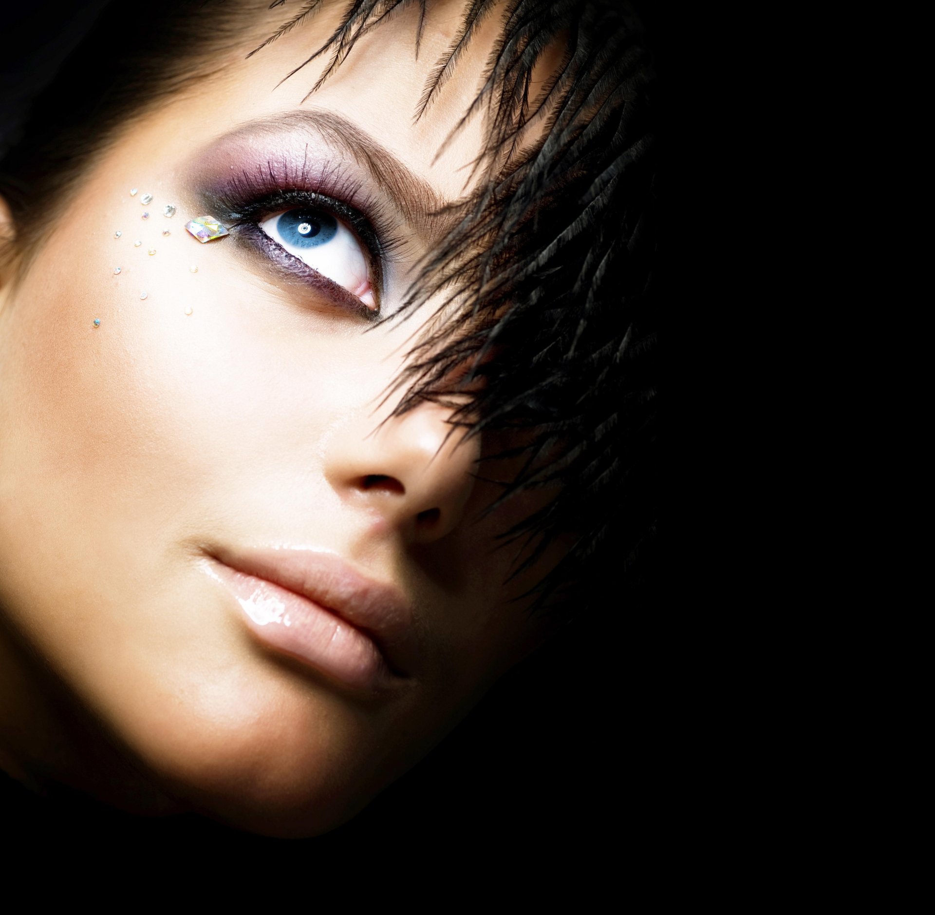 ragazza sfondo nero occhio piume strass trucco