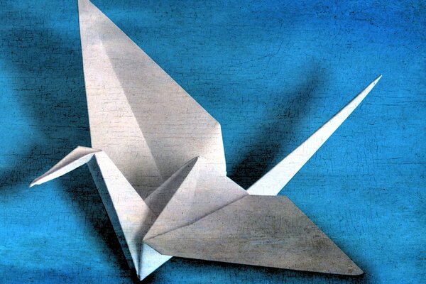 Origami aus Papier, Kraniche auf blauem Hintergrund