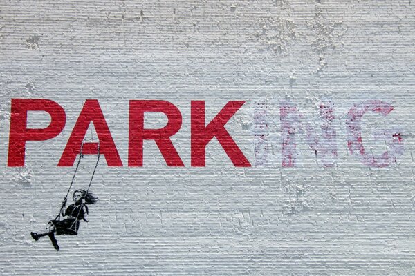 A girl is swinging on a swing, next to a wall painted with graffiti