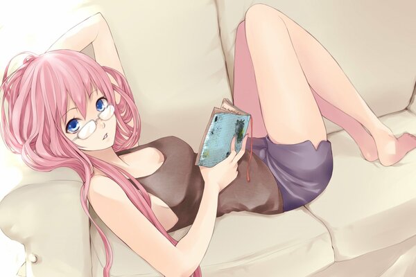 A girl with glasses is lying on the sofa and reading a book