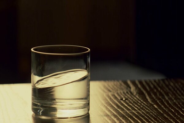 Un vaso de agua en una mesa de madera