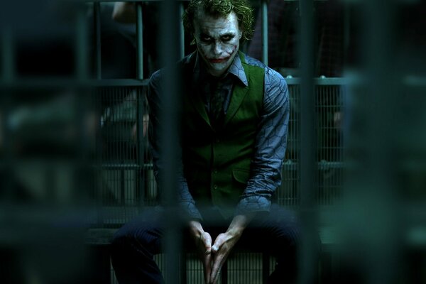Joker siedzący za kratkami, ze smutnym spojrzeniem