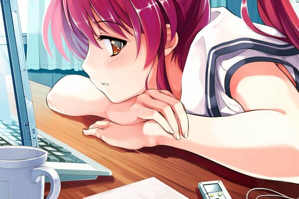 The girl with red hair is sitting at the computer sad