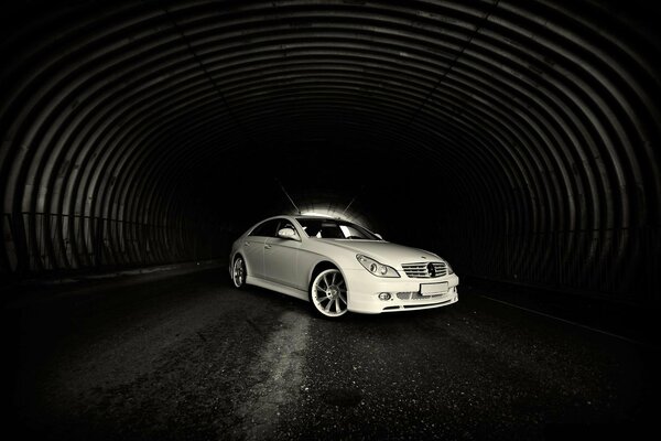 Une mercedes blanche se tient dans un tunnel sombre