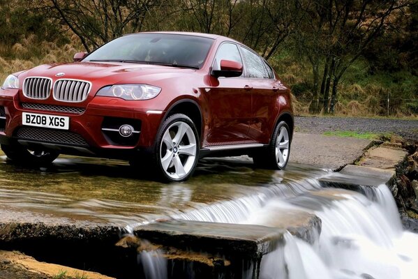 Bmw near the waterfall in nature by the trees