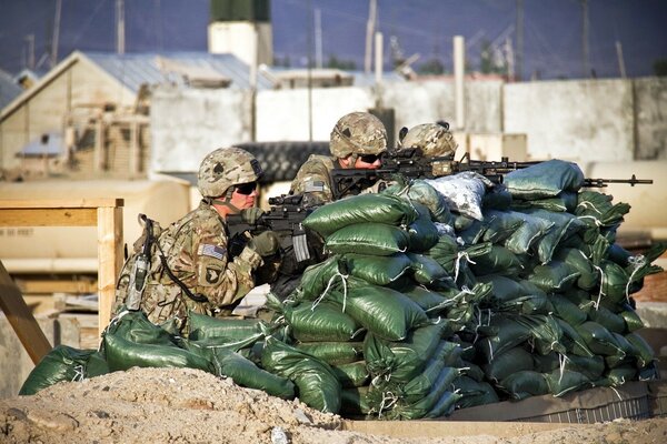 Soldiers with weapons are sitting in ambush